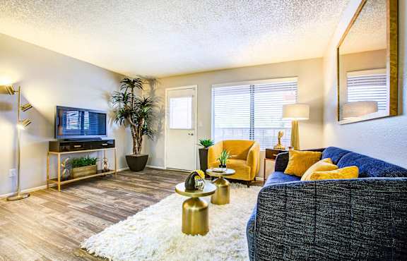 A living room with a grey couch, a white rug, and a gold coffee table at Elevation Apartments, Tucson, AZ