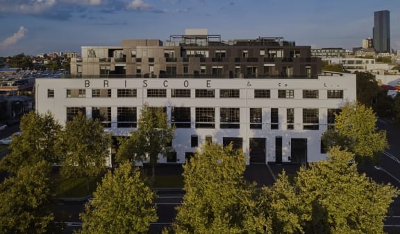 an aerial view of a white building with trees in front of it