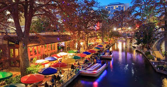 a city at night with colorful umbrellas and boats on the river  at The Frederick, San Antonio, TX, 78240
