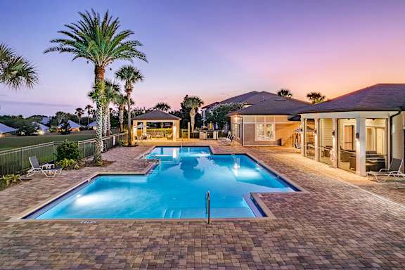 A house with a pool surrounded by palm trees.
