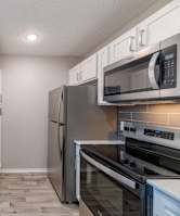 A kitchen with a stainless steel refrigerator, microwave, and oven.