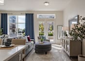 Thumbnail 11 of 21 - Living room with a grey ottoman and a white table at 200 City View, Provo, UT, 84601