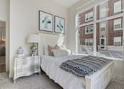 Thumbnail 14 of 21 - Bedroom with a large bed, a dresser, and a window overlooking a brick building at 200 City View, Provo, 84601