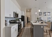 Thumbnail 5 of 21 - A modern kitchen with white cabinets and a large island.