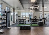 Thumbnail 18 of 42 - A gym with a variety of equipment including weights, machines, and a green mat. 605 Place Student Housing & Co-Living, St George, 84770