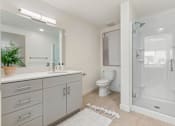 Thumbnail 11 of 25 - A white bathroom with a toilet, sink, and shower.