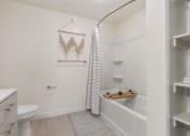 Thumbnail 14 of 25 - A white bathroom with a toilet, sink, and a shower curtain.