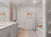 Thumbnail 15 of 25 - A bathroom with a toilet, sink, and a shower curtain.