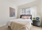 Thumbnail 9 of 25 - A bedroom with a large bed, a nightstand, and a painting on the wall.