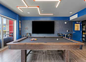 Thumbnail 1 of 62 - A pool table in a room with a blue wall and a television.