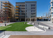 Thumbnail 19 of 62 - A modern building with a grassy area in front.