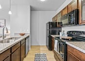 Thumbnail 10 of 26 - A modern kitchen with dark wood cabinets and black appliances.