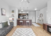 Thumbnail 1 of 26 - A modern living room with a grey couch and a bar area.