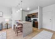 Thumbnail 7 of 26 - A kitchen with a bar stool and a counter.