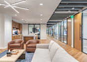 Thumbnail 19 of 19 - A modern office lounge with brown leather chairs and a white sofa.