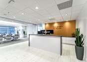 Thumbnail 14 of 19 - A reception area with a white reception desk and a cactus plant on the right.