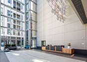 Thumbnail 3 of 18 - A modern building with a glass facade and a reception area with a long counter.