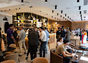 Thumbnail 9 of 15 - A group of people are gathered in a room with a bar area.
