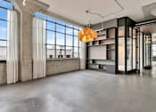 Thumbnail 4 of 25 - A large, empty room with a concrete floor and a large window with white curtains.