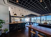 Thumbnail 11 of 24 - A modern kitchen with a long wooden counter and bar stools.