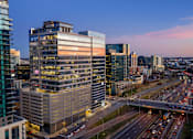 Thumbnail 14 of 24 - A cityscape with a highway and buildings during twilight.