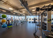 Thumbnail 15 of 24 - A gym with a variety of equipment and a view of the city.