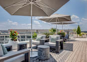 Thumbnail 2 of 15 - A patio with a large umbrella and a table with a vase of flowers on it.