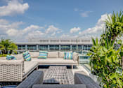Thumbnail 3 of 15 - A patio with a couch and pillows overlooking a building.