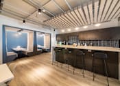 Thumbnail 3 of 24 - A modern bar area with a long counter and stools.
