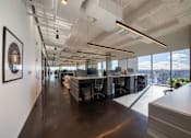 Thumbnail 7 of 24 - A modern office space with a long hallway, desks, and a view of the city.