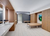 Thumbnail 7 of 15 - A modern room with wooden cabinets and a bench.