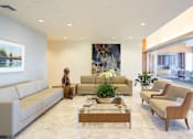 Thumbnail 13 of 18 - A living room with a white sofa, a wooden coffee table, and a large painting on the wall.