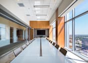 Thumbnail 14 of 18 - A long white table is in a conference room with a view of the city.