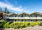 Thumbnail 8 of 8 - Apartment building with green bushes in front.