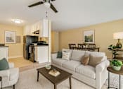 Thumbnail 2 of 8 - A living room with a white couch and a coffee table.