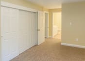 Thumbnail 8 of 8 - A hallway with a white door on the left and a carpeted floor.
