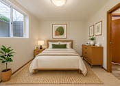 Thumbnail 7 of 8 - A bedroom with a bed, nightstand, and plant.