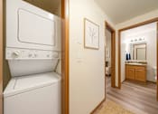 Thumbnail 1 of 8 - A white washing machine in a small laundry room.