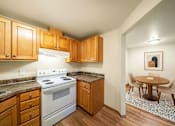 Thumbnail 3 of 8 - A kitchen with a white stove top oven and wooden cabinets.