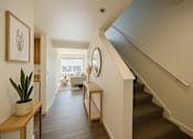 Thumbnail 1 of 8 - A hallway with a staircase and a mirror on the wall.