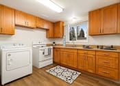 Thumbnail 6 of 8 - A kitchen with wooden cabinets and white appliances.