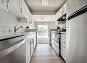 Thumbnail 3 of 8 - A modern kitchen with white cabinets and stainless steel appliances.