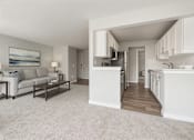 Thumbnail 4 of 8 - A well-lit, spacious kitchen and living room with a grey carpet.
