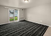 Thumbnail 7 of 8 - A room with a black carpet and a sliding glass door leading to a balcony.