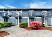 Thumbnail 8 of 8 - A blue building with a flower bed in front.