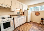 Thumbnail 6 of 8 - A kitchen with white appliances and wooden floors.