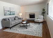 Thumbnail 2 of 8 - A living room with a grey couch, a coffee table, and a painting on the wall.