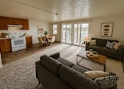 Thumbnail 3 of 8 - A living room with a grey couch and a dining table.