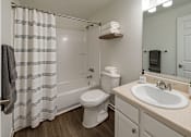 Thumbnail 5 of 8 - A white toilet sits next to a sink in a small bathroom.
