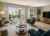 Thumbnail 6 of 8 - A living room with a grey couch, a blue armchair, a coffee table, and a balcony with a view of a building.